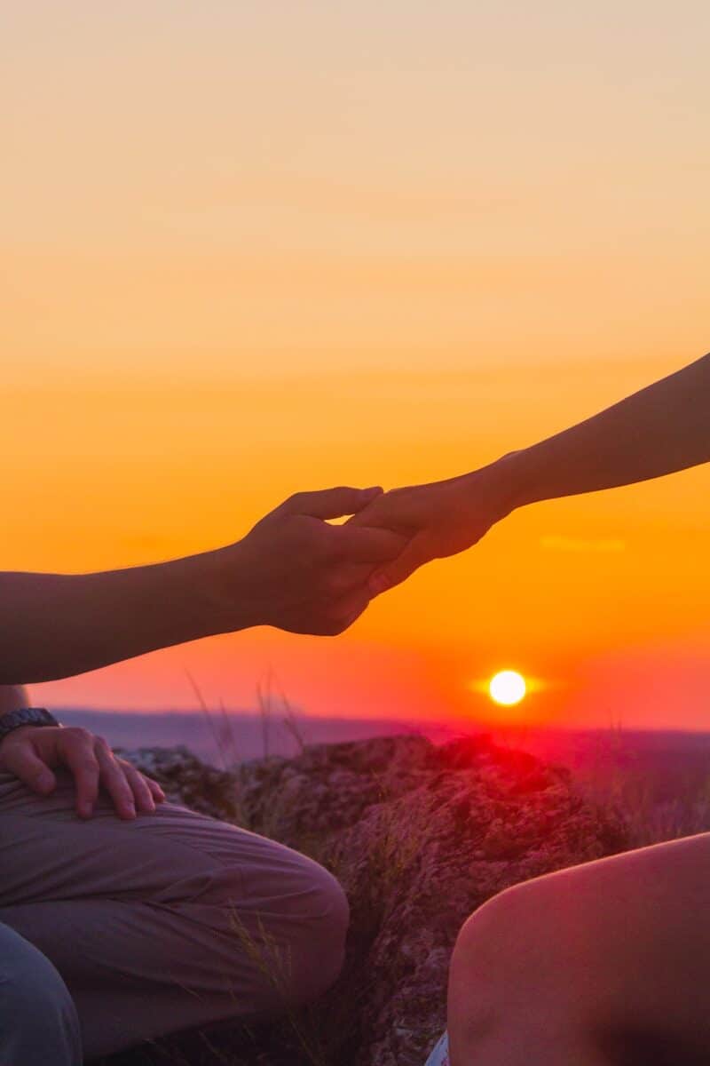 Paar hält sich die Hände bei Sonnenuntergang